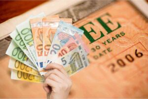 Buono fruttifero e soldi in euro in una mano