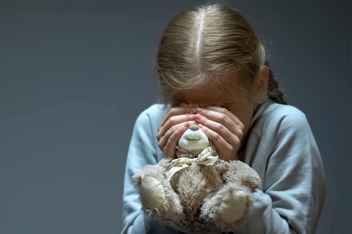 bambina terrorizzata con peluche in mano