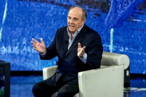 Gerry Scotti seduto in tv