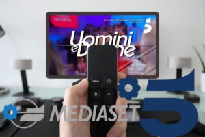tv con uomini e donne, mano con telecomando e logo Mediaset Canale 5