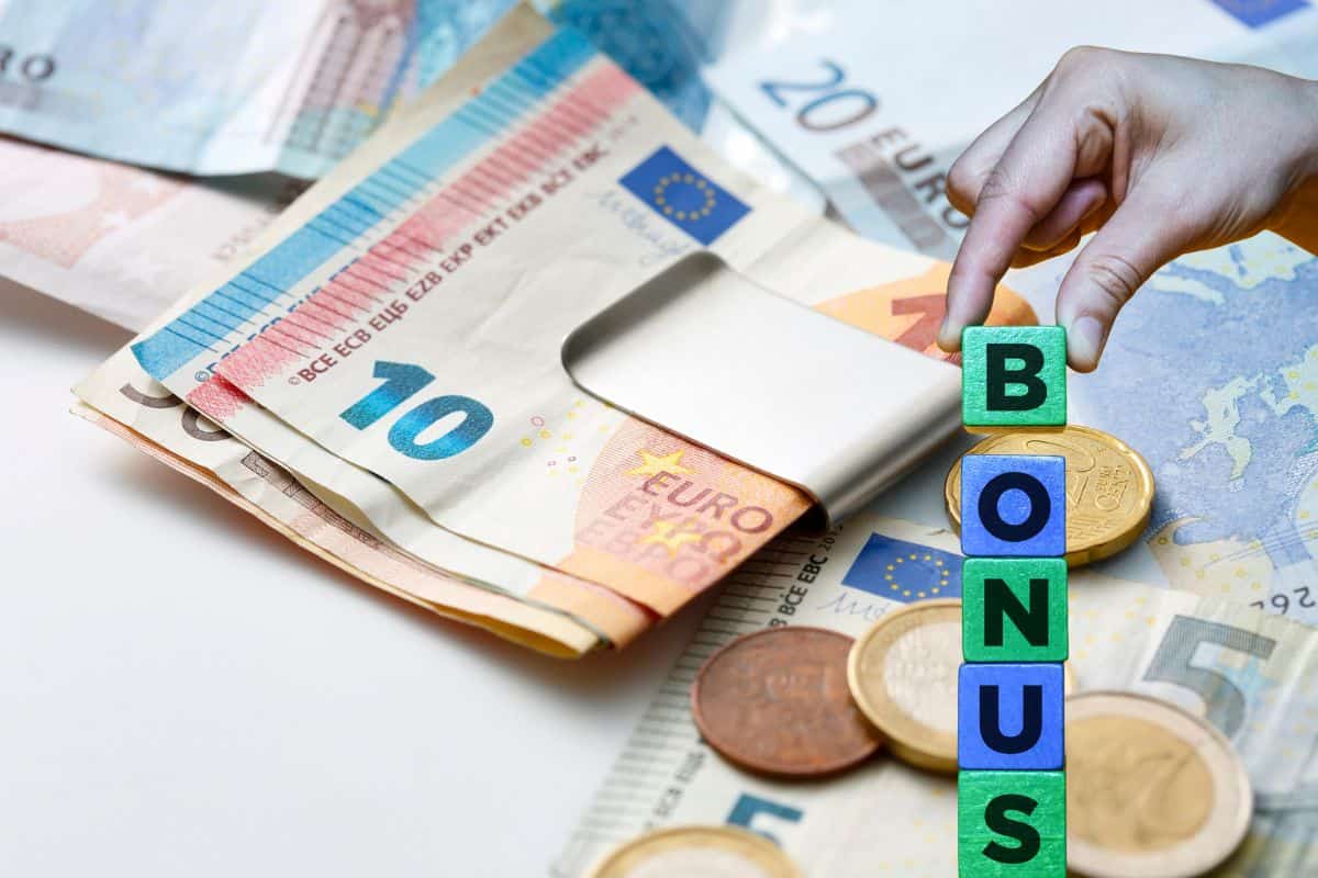 banconote euro con mano che compone la scritta bonus con delle caselle